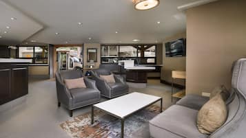A modern living area with a sofa, two armchairs, a coffee table, and a TV.