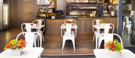 A restaurant with a bar area, white chairs, and a counter with a menu display.