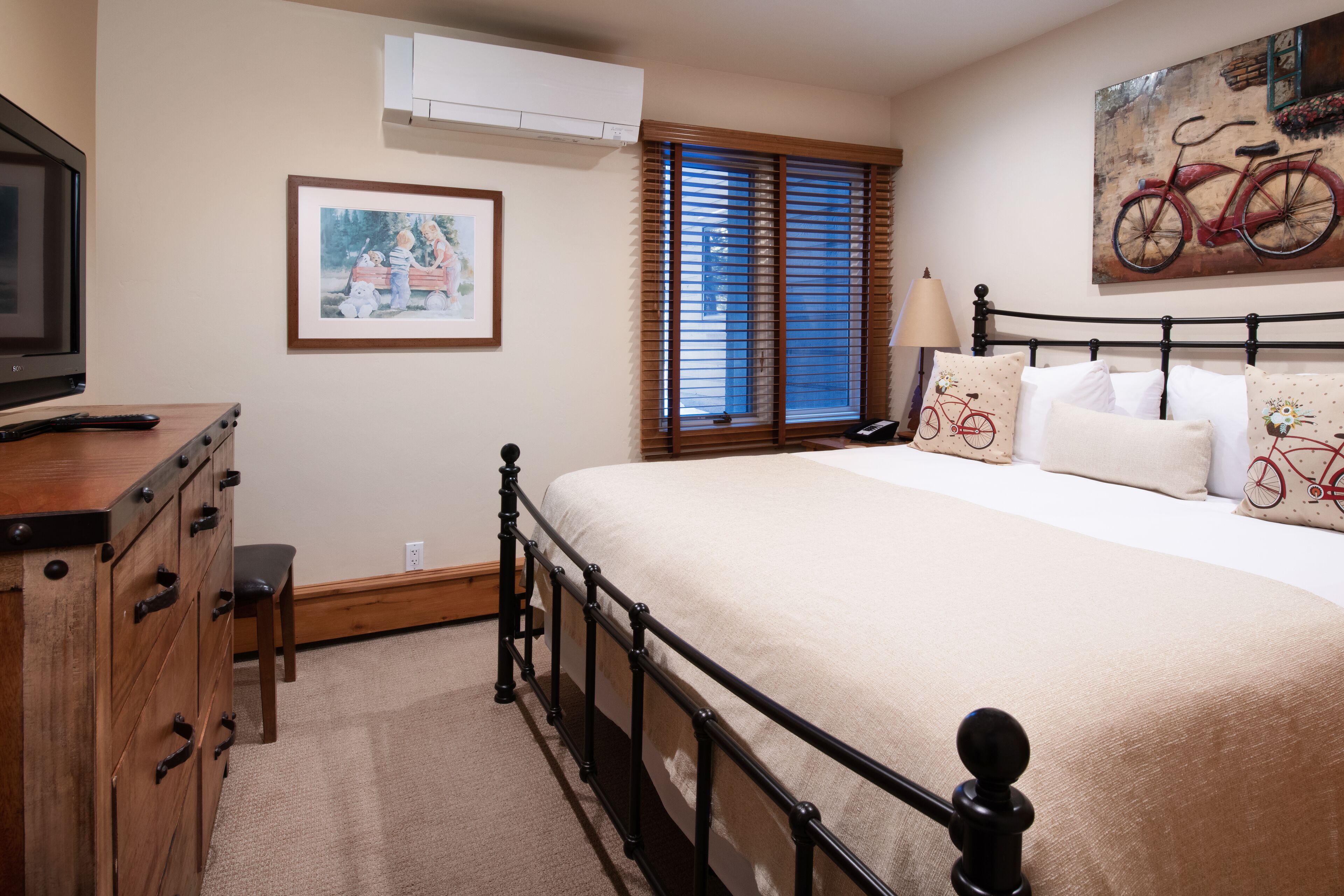 A bedroom with a bed, dresser, and a painting on the wall.