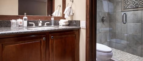 Ein Badezimmer mit einer Granittafel, Holzausstattung, einer weißen Toilette und einer Dusche mit schwarz-weiß karierter Wand.