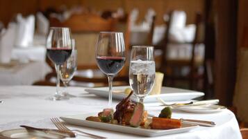 A dining table set with plates, cutlery, and glasses of wine.