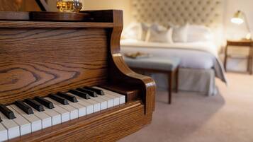 A grand piano in a hotel room with a bed and a nightstand.