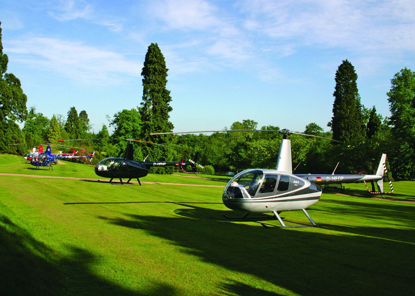 A helicopter on a grassy field with trees in the background.
