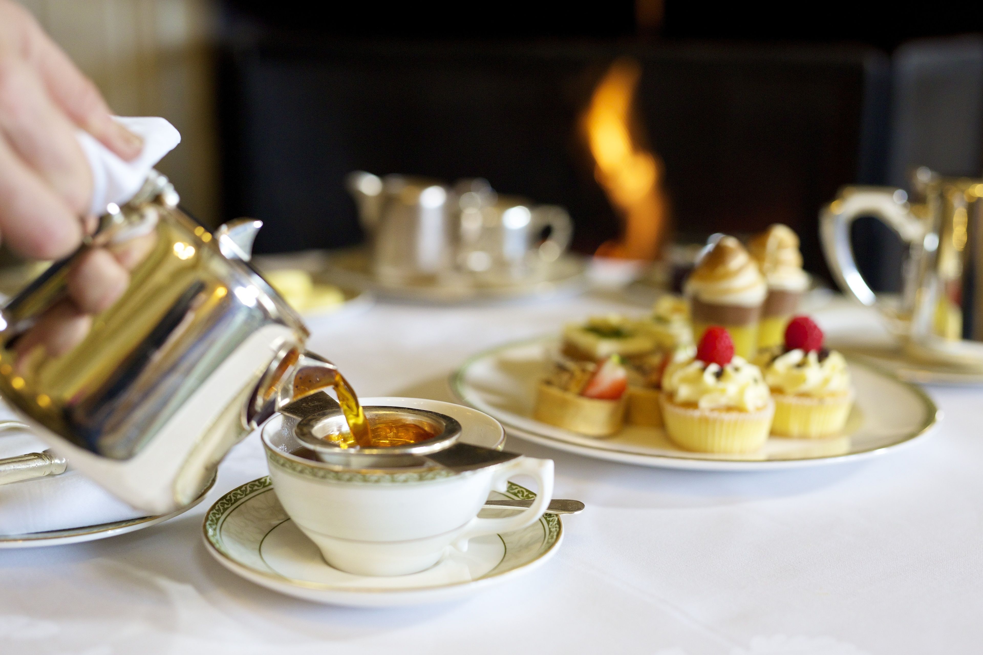 A table set with tea service and desserts, including cupcakes and a teapot.