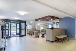 A spacious lobby with a reception desk, seating area, and a staircase leading to an upper level. - Holiday Inn Express and Suites Albany Airport- Wolf Road by IHG (Albany)