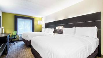 A hotel room with two beds, a desk, a chair, and a window.