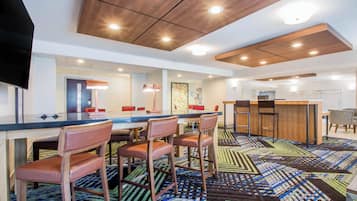 A modern hotel room with a dining area, a bar, and a TV.