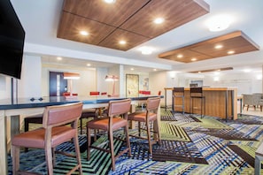 A modern hotel room with a dining area, a bar, and a TV. - Holiday Inn Express and Suites Albany Airport- Wolf Road by IHG (Albany)