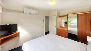 A hotel room with a bed, a TV on a wooden stand, a wardrobe, and a mirror.