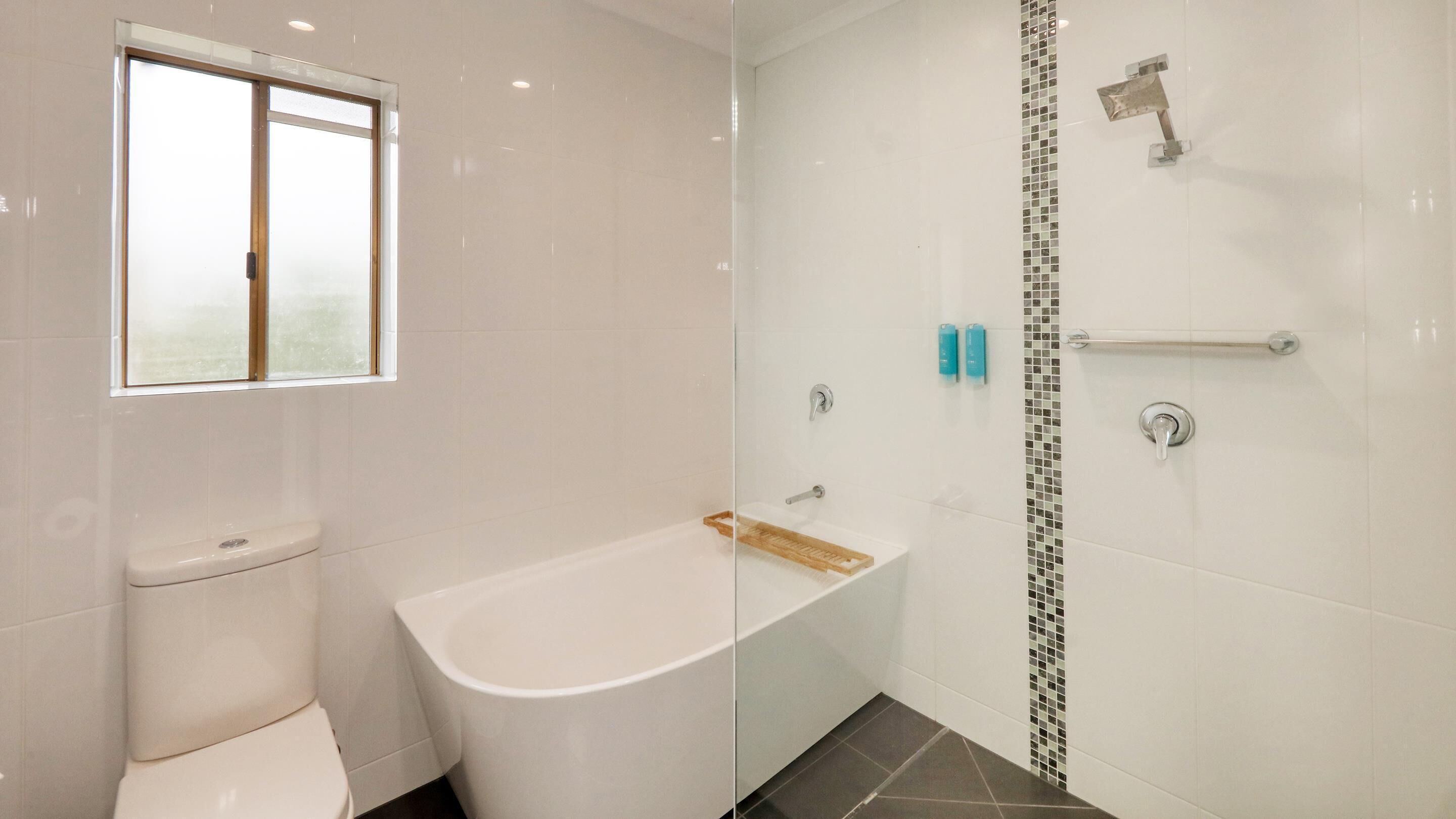 A modern bathroom with a toilet, bathtub, and shower.