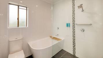 A modern bathroom with a toilet, bathtub, and shower.
