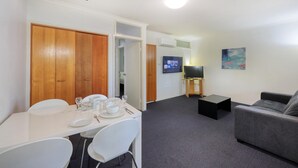Ein kompakter Wohnraum mit Essbereich, einer Couch, einem Fernseher und einem Gemälde an der Wand.