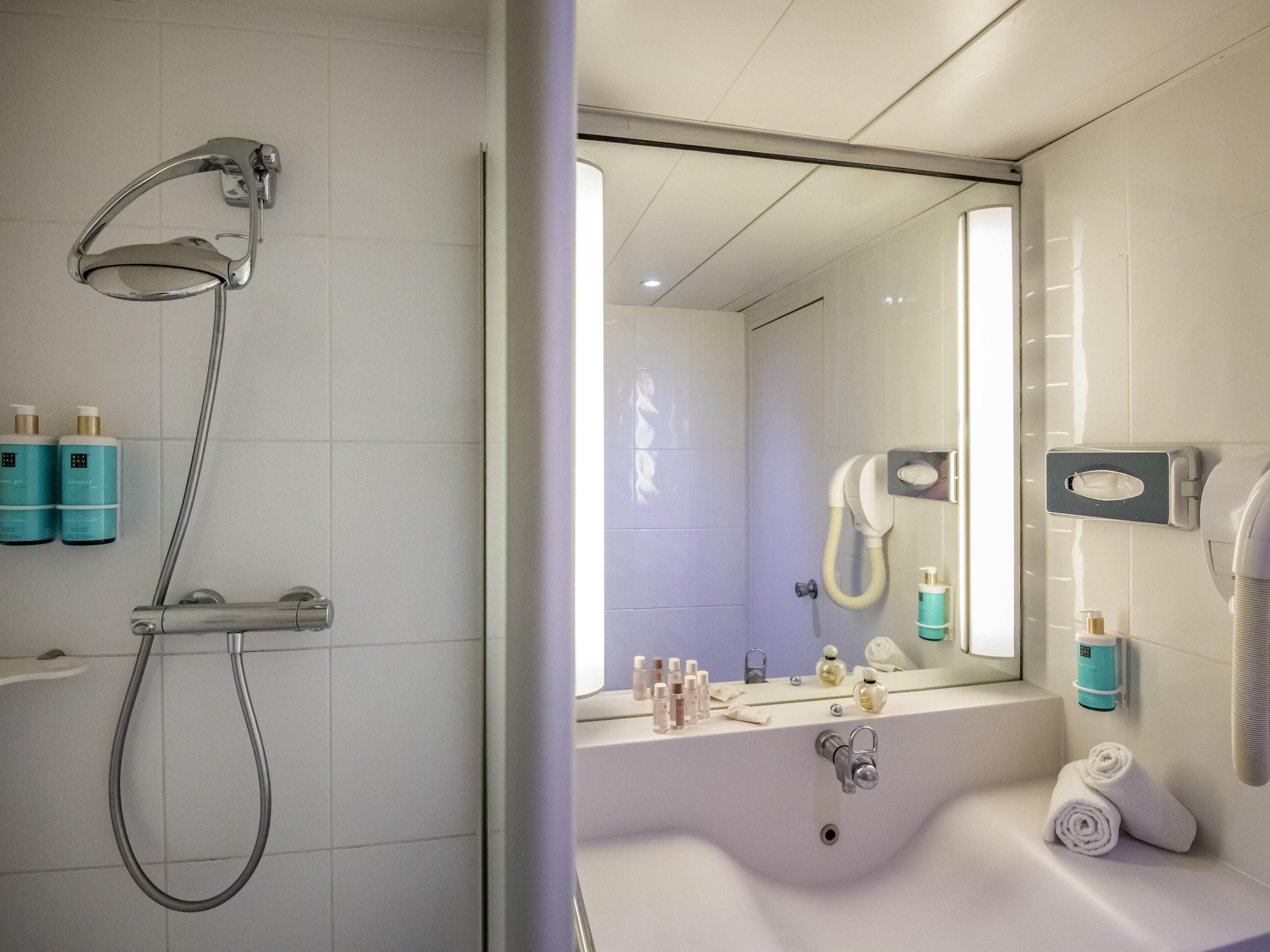 Une salle de bain moderne avec une douche, un lavabo et un miroir.