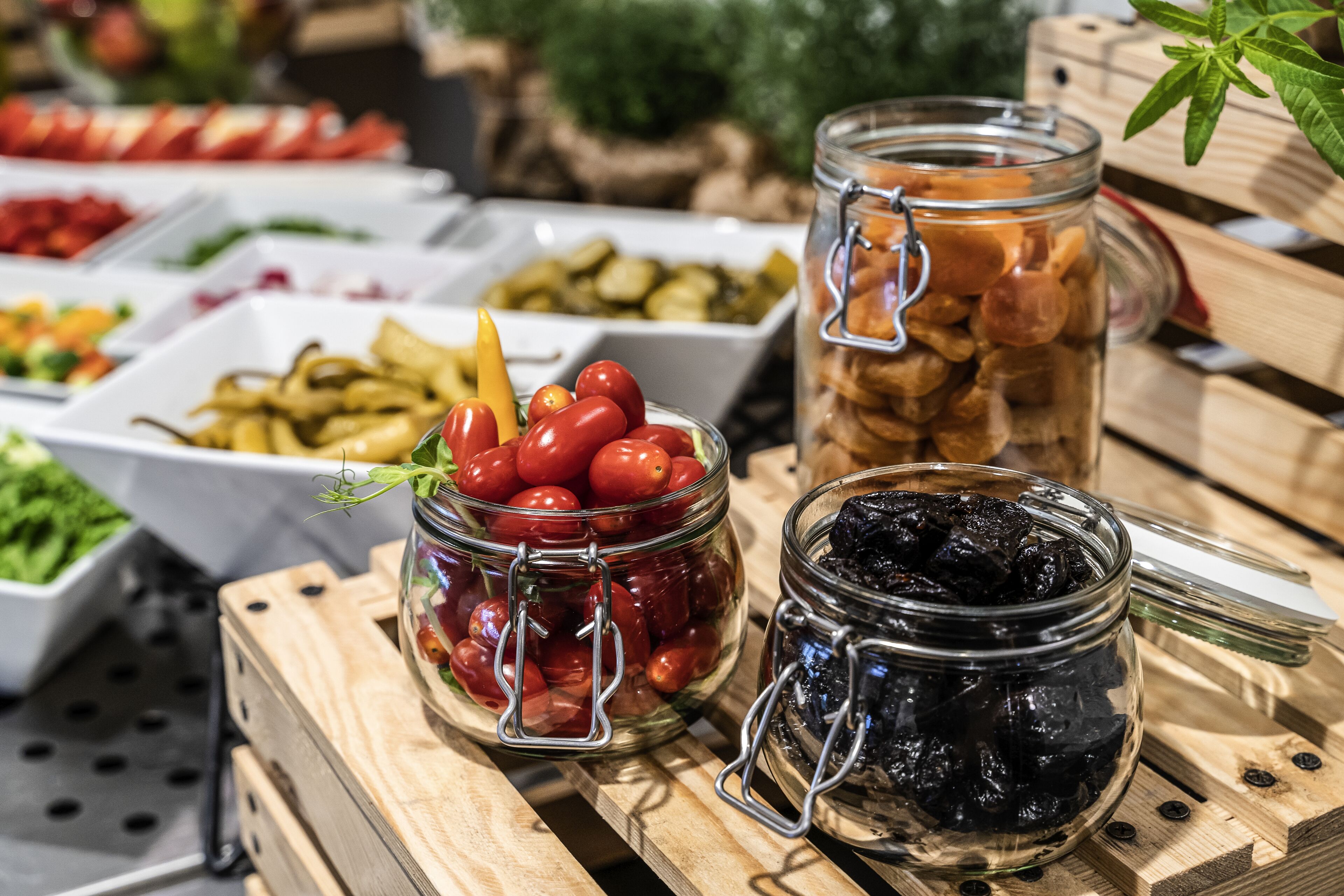 Exposição de comida com diversos pratos e potes de frutas e vegetais em conserva.