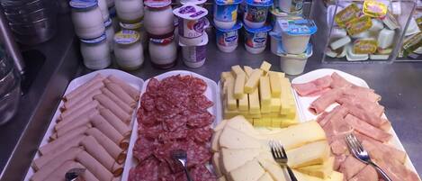 A buffet with various food items including meats, cheeses, and yogurt.
