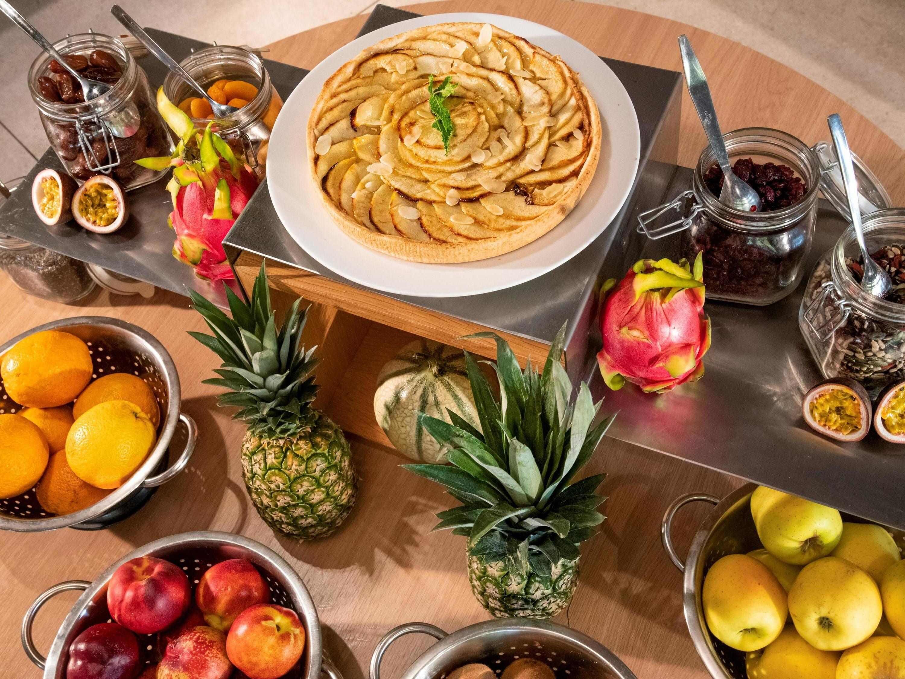 Una mesa con diversas frutas y un plato de tarta de manzana.