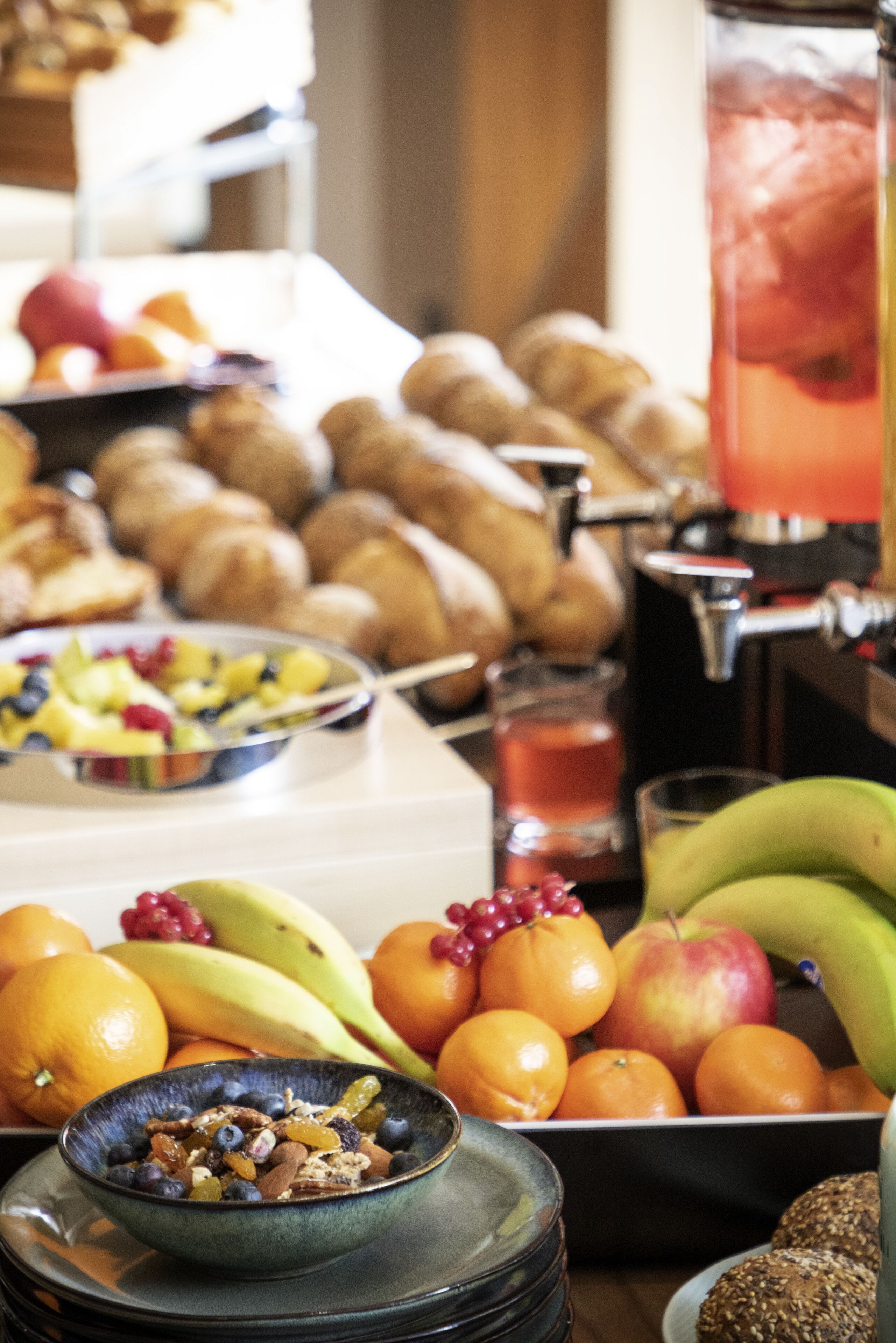 Ein Buffet mit Früchten, Gebäck und einem Saftspender.