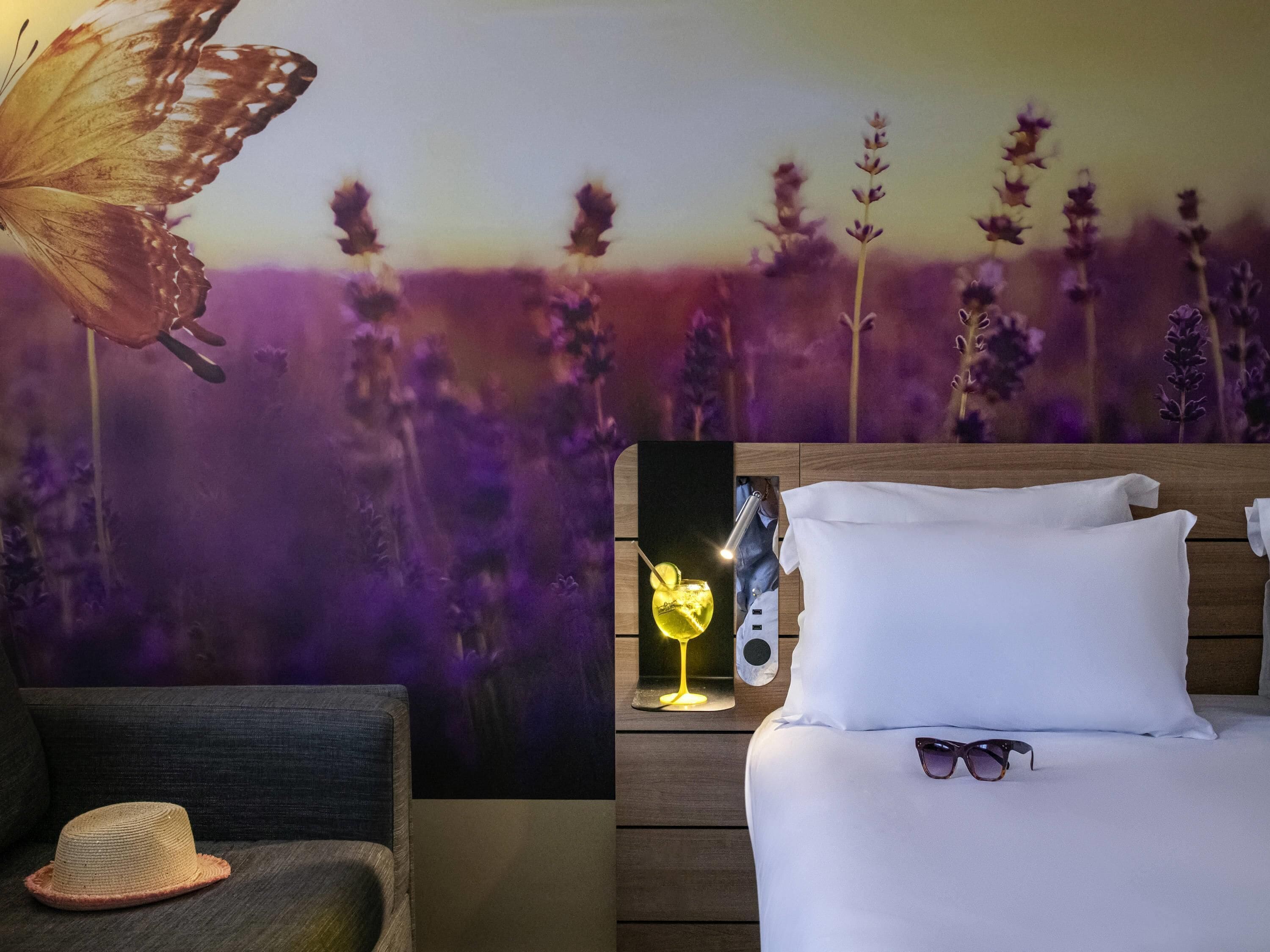 A bedroom with a bed, pillows, a hat, and a wall mural.