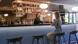 Un espace bar avec des tabourets, un comptoir et une variété de bouteilles et de verres.