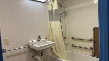 Un baño con lavamanos blanco, ducha con puerta de cristal y armario de madera.