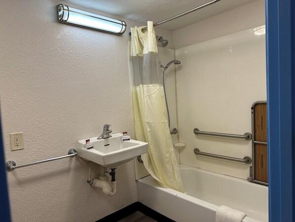 A bathroom with a white sink, a shower with a glass door, and a wooden cabinet.