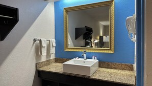A bathroom with a white sink, a gold-framed mirror, and a towel rack with white towels.