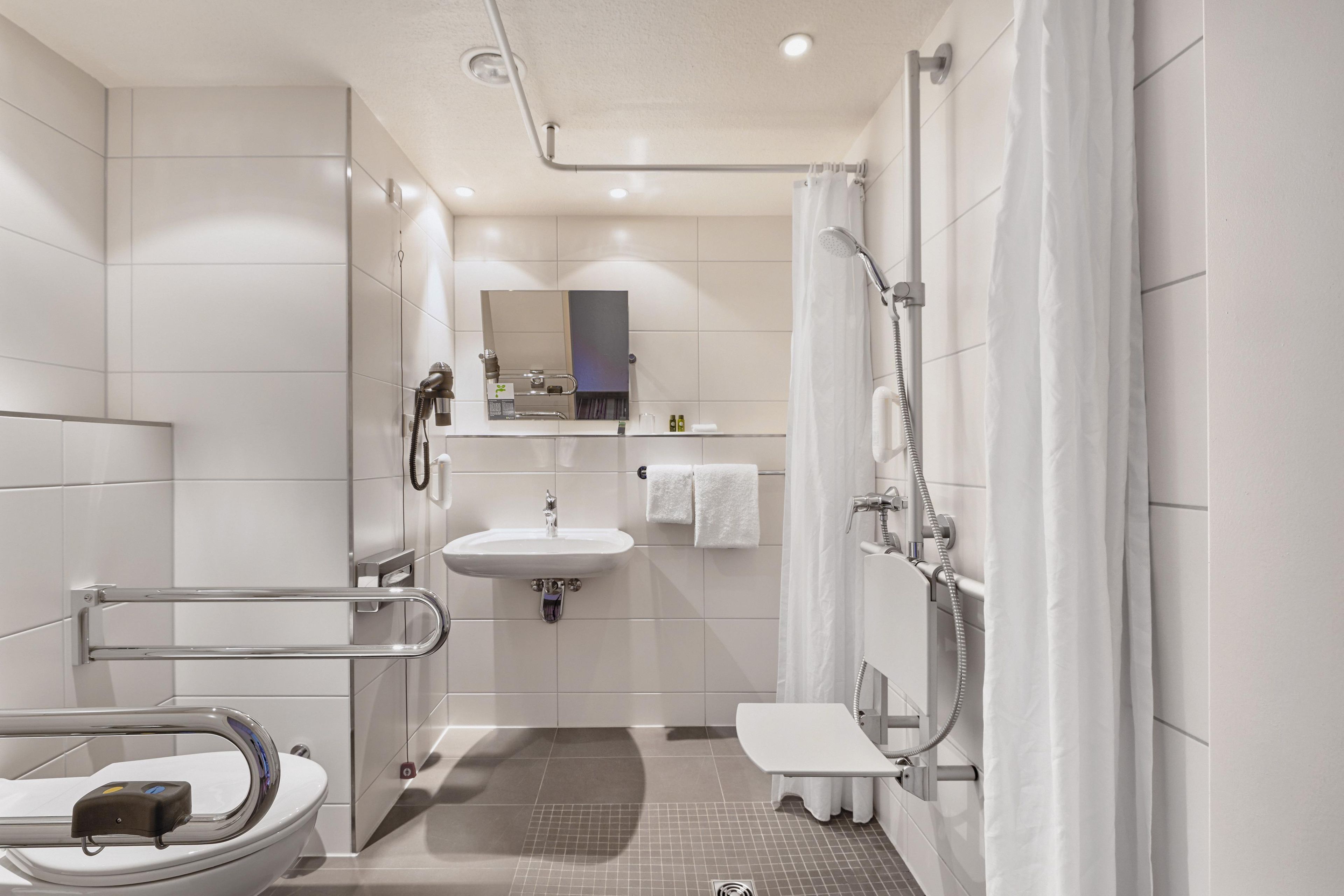 Ein modernes Badezimmer mit Toilette, Waschbecken, Dusche und Spiegel.