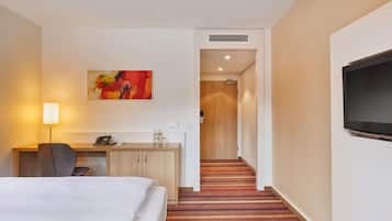 Une chambre d’hôtel avec un lit, un bureau, une chaise, un téléphone et un tableau au mur.
