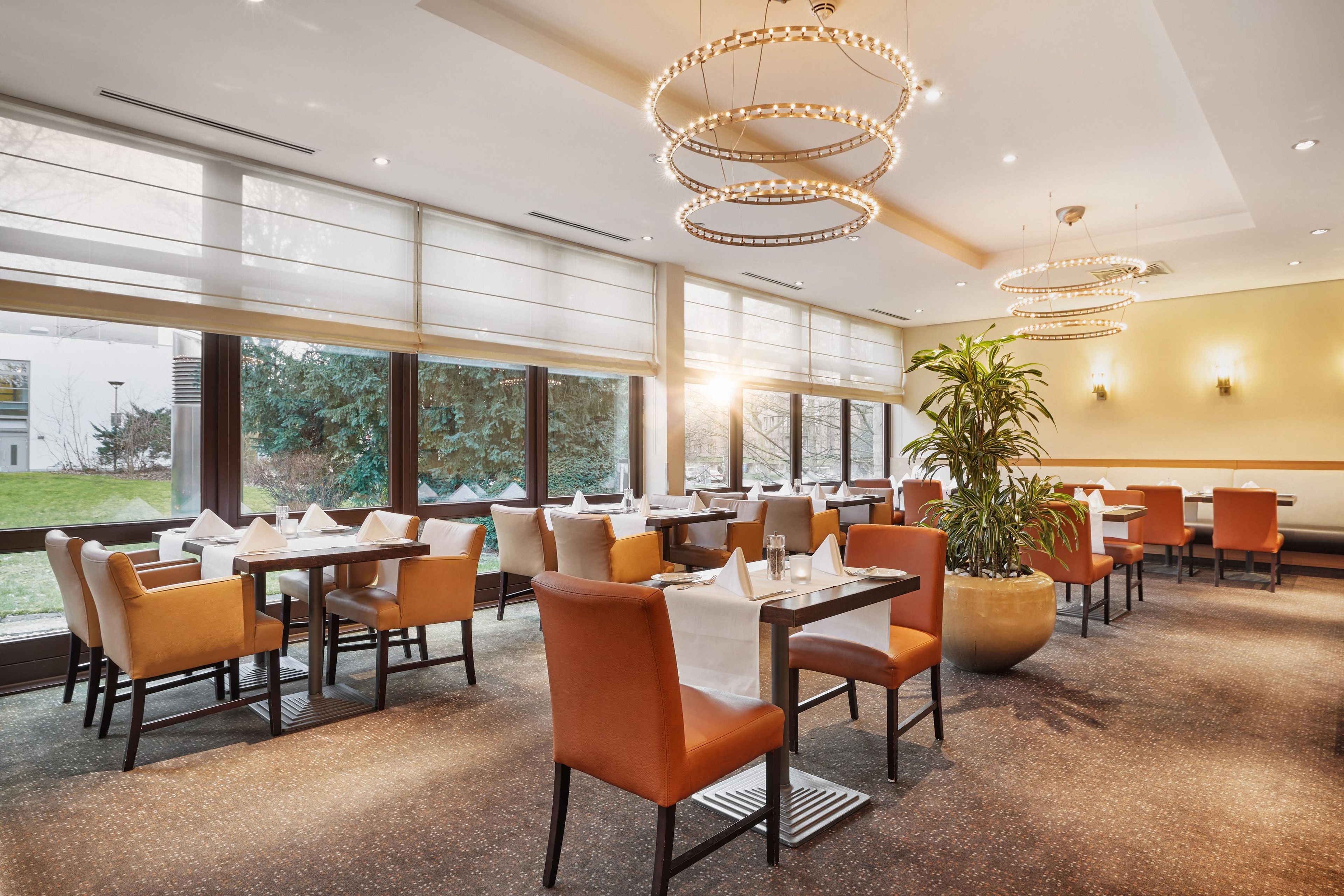 A restaurant with multiple tables, chairs, and a large window offering a view of the outdoors.