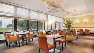 A restaurant with multiple tables, chairs, and a large window offering a view of the outdoors.