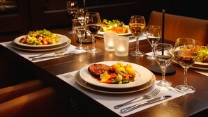 Une table à manger dressée avec des assiettes remplies de nourriture, des verres à vin et des couverts.