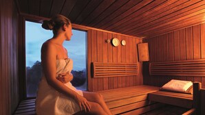 A person sitting on a wooden bench in a room with wooden walls and a window. - Best Western Hotel Bochum (Bochum)