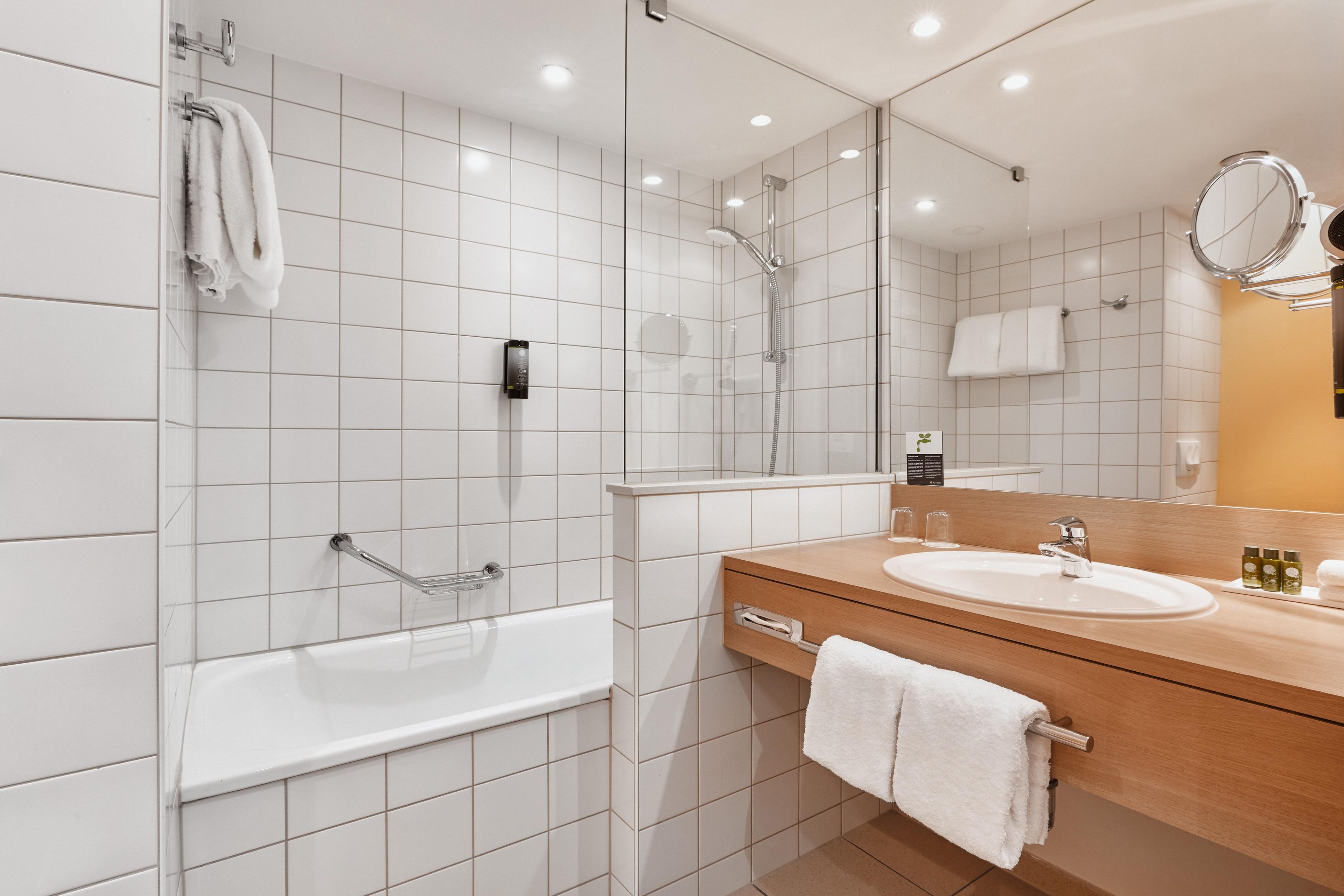 A modern bathroom with a bathtub, a shower, a vanity with a sink, and a mirror.