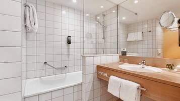 A modern bathroom with a bathtub, a shower, a vanity with a sink, and a mirror.