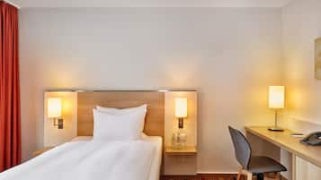 Ein Hotelzimmer mit einem Bett, zwei Nachttischlampen, einem Schreibtisch mit Stuhl und einem Telefon.
