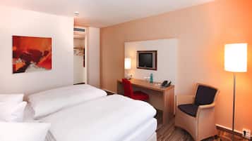 A hotel room with two beds, a desk with a chair, a TV, and a lamp.