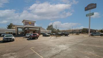 A parking lot with several cars, a La Quinta hotel, and a sign indicating amenities like an indoor pool, hot tub, meeting room, WiFi, and free breakfast.