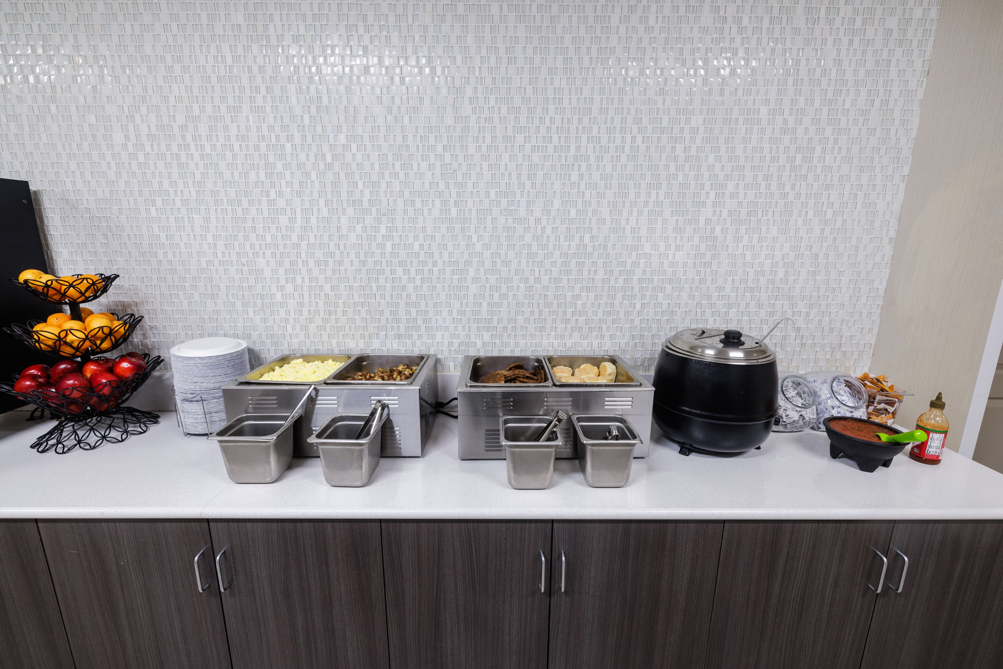 Una mesa de buffet con varios recipientes de comida y un bol de fruta.