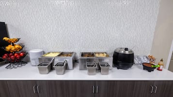 Ein reichhaltiges Buffet mit verschiedenen Speisebehältern und einer Obstschale.