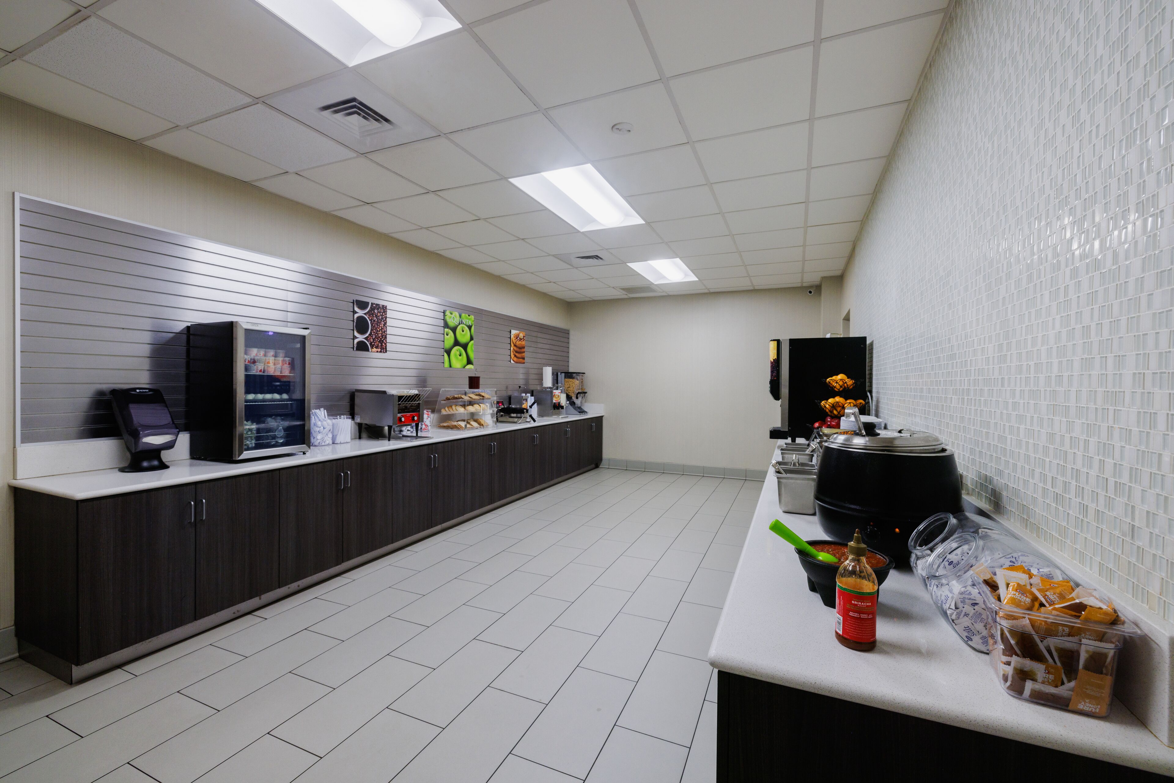 A modern kitchen with a long counter, a coffee machine, and various food items.