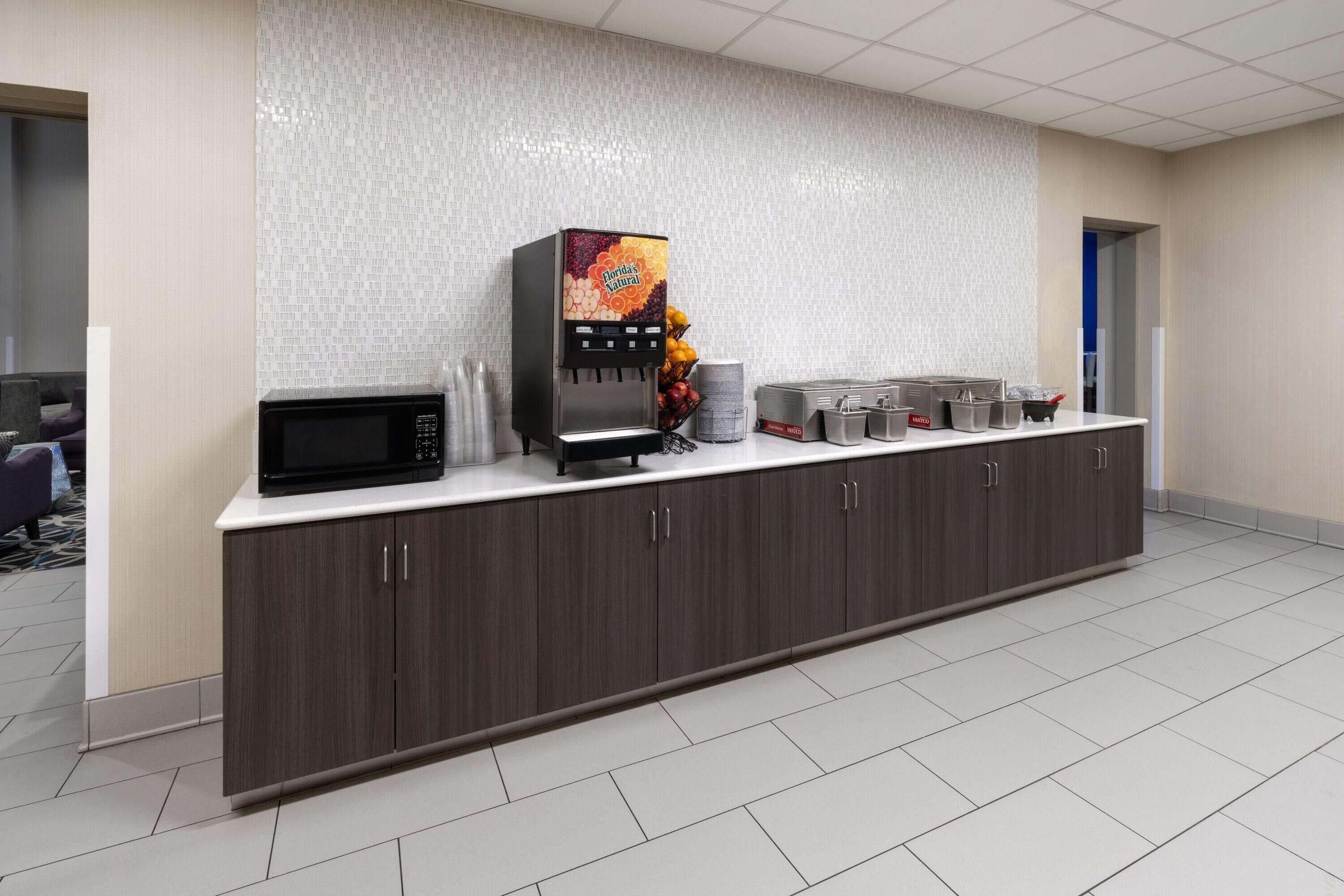 A modern kitchen area with a coffee machine, microwave, and various kitchen utensils on a counter.