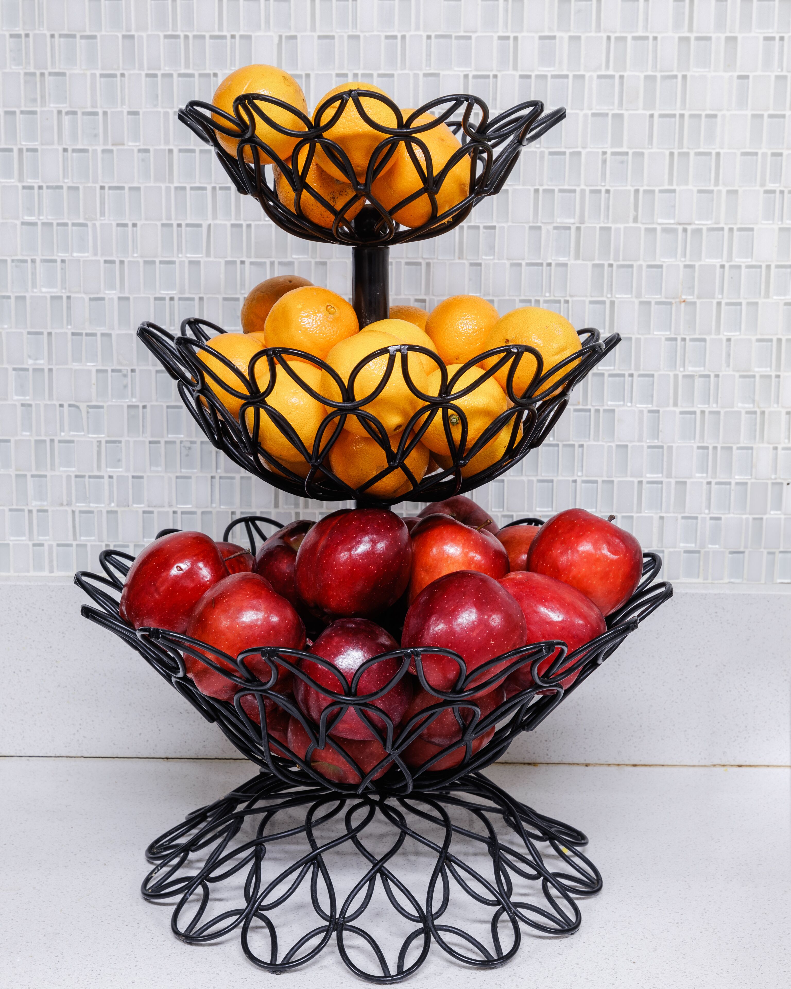 A three-tiered fruit stand with oranges and apples.