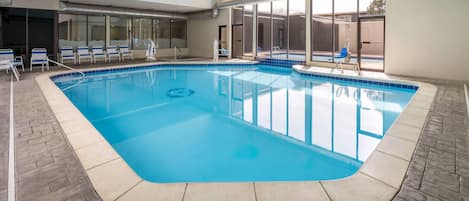 An indoor swimming pool with clear blue water, tiled edges, and a tiled floor.