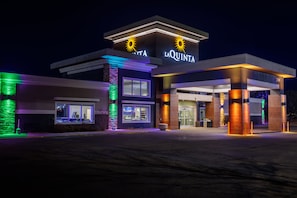 A hotel with a modern design, featuring a prominent sign with sun motifs and the name 'La Quinta'.