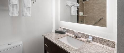 Une salle de bain avec un lavabo blanc, un meuble en bois foncé et un grand miroir.