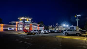 Een hotel met een modern design, een parkeerplaats en een bord waarop voorzieningen staan zoals een jacuzzi en gratis ontbijt.