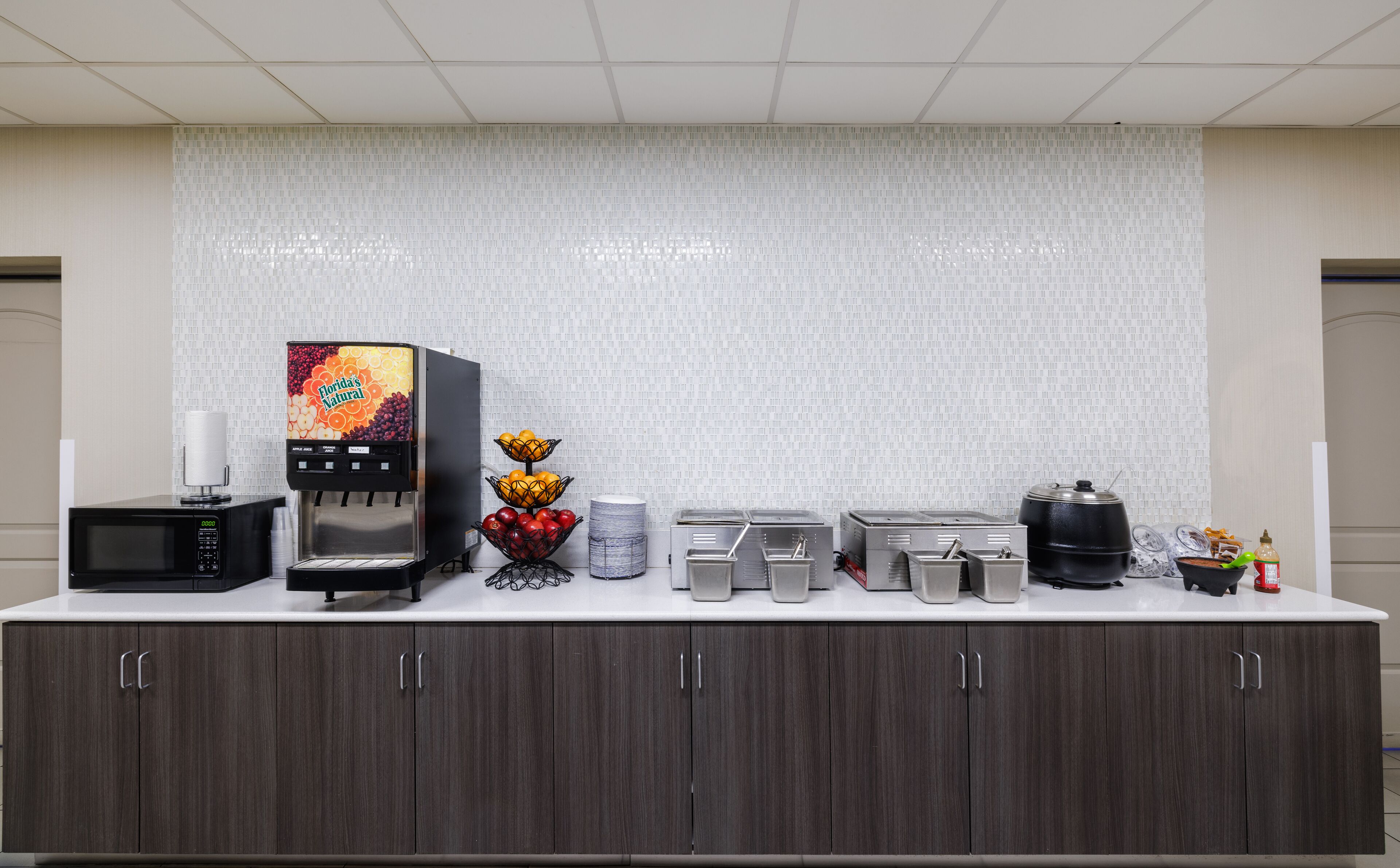 A self-service coffee station with a coffee machine, a microwave, and various food items.