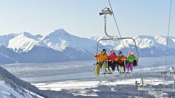 A group of people on a ski lift with snow-covered mountains in the background.