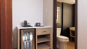 Ein kleines Badezimmer mit Toilette, einem kleinen Waschbecken und einem Kühlschrank mit Wasserflaschen.