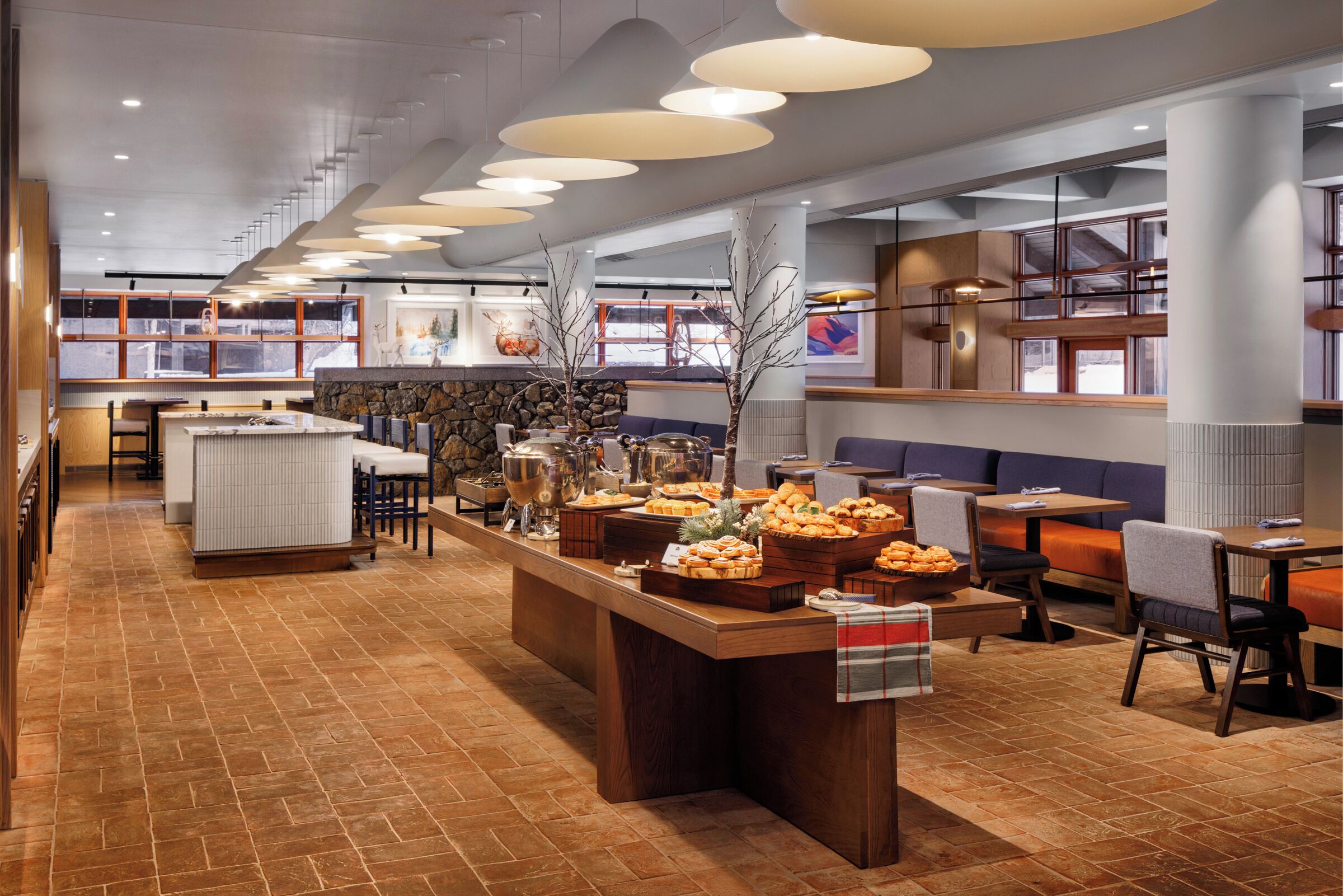 A buffet area with a variety of food items, seating arrangements, and a stone wall backdrop.